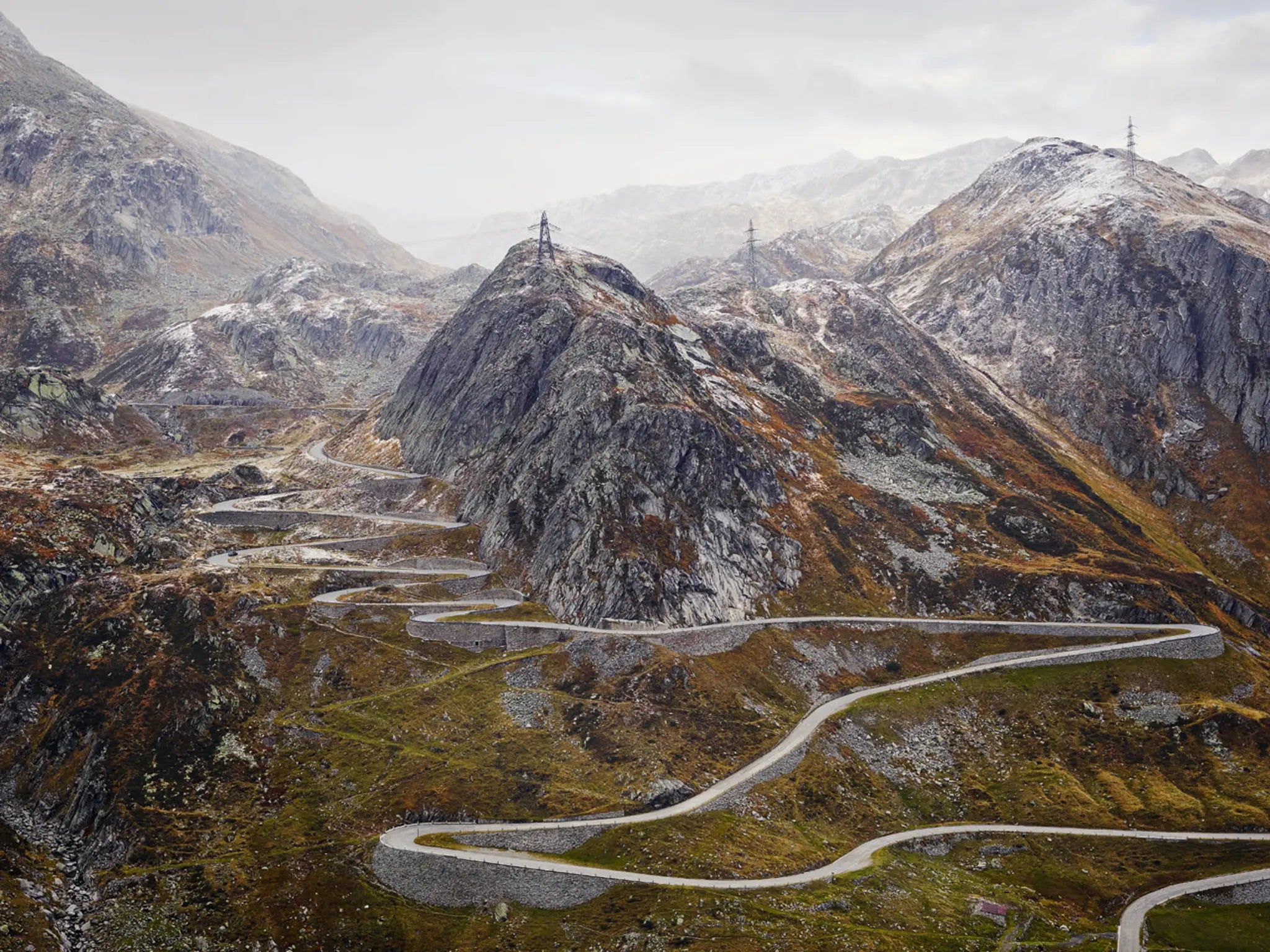 Winding mountain road in a mountainous landscape with snow-capped peaks.